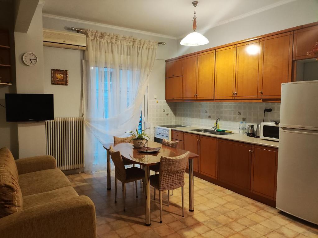 a kitchen with a table and a couch and a kitchen with a refrigerator at Άνετο διαμέρισμα στο κέντρο της πόλης in Xanthi