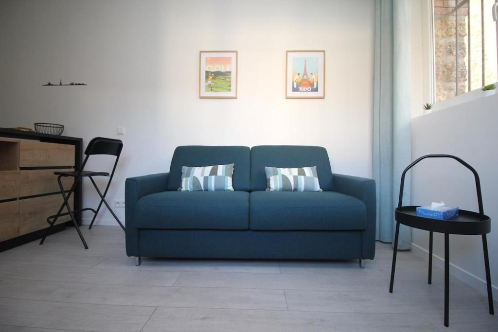 un canapé bleu dans un salon avec une table dans l'établissement Studio à Cormeilles-en-Parisis, à Cormeilles-en-Parisis