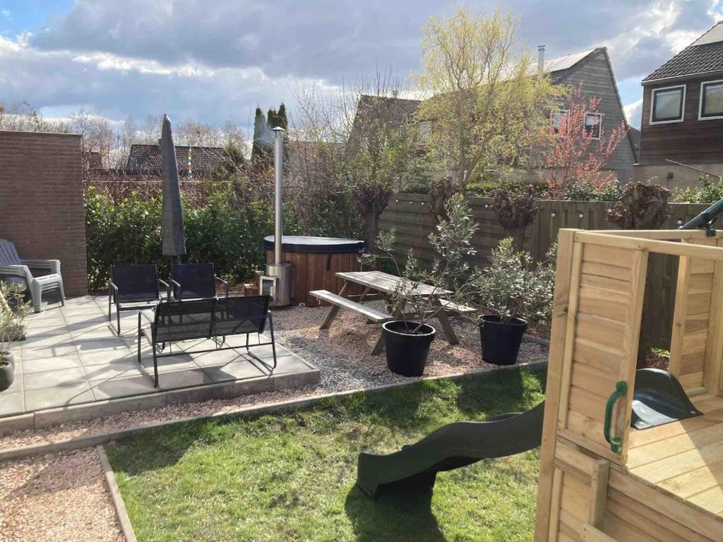 a patio with a bench and a table in a yard at Het Steven van Grou - luxury wellness house with hot tub in Grou
