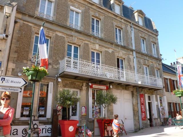 a large brick building with a balcony on a street at Studio De La Mer in Arromanches-les-Bains