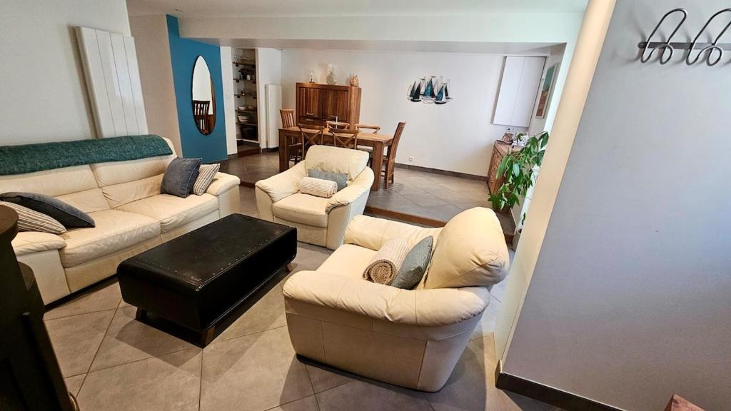 a living room with couches and chairs and a table at Maison de bourg proche de la mer in Ouistreham
