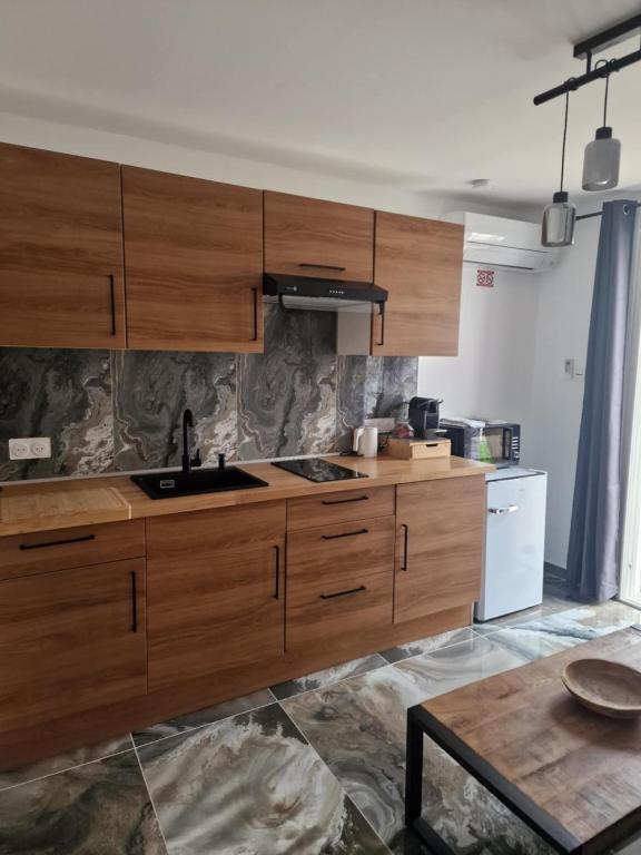 une cuisine avec des placards en bois et une table dans l'établissement Résidence Dica T2, à Port-Saint-Louis-du-Rhône