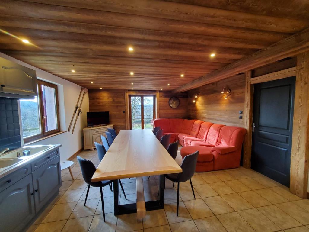 a living room with a table and a red couch at Chalet de la Rougeterre in Le Ménil