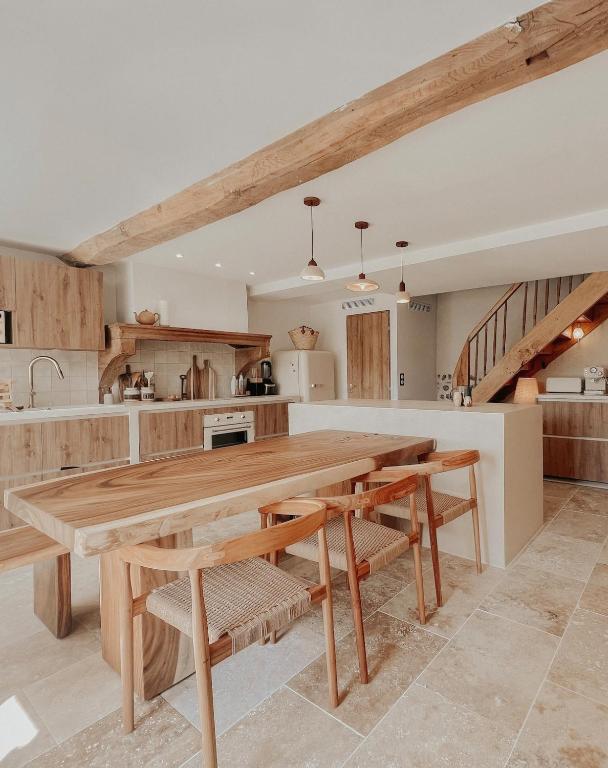 une grande cuisine avec une table et des bancs en bois dans l'établissement Charmante maison en pierres, séjour à la ferme, à Saint-Georges-dʼEspéranche
