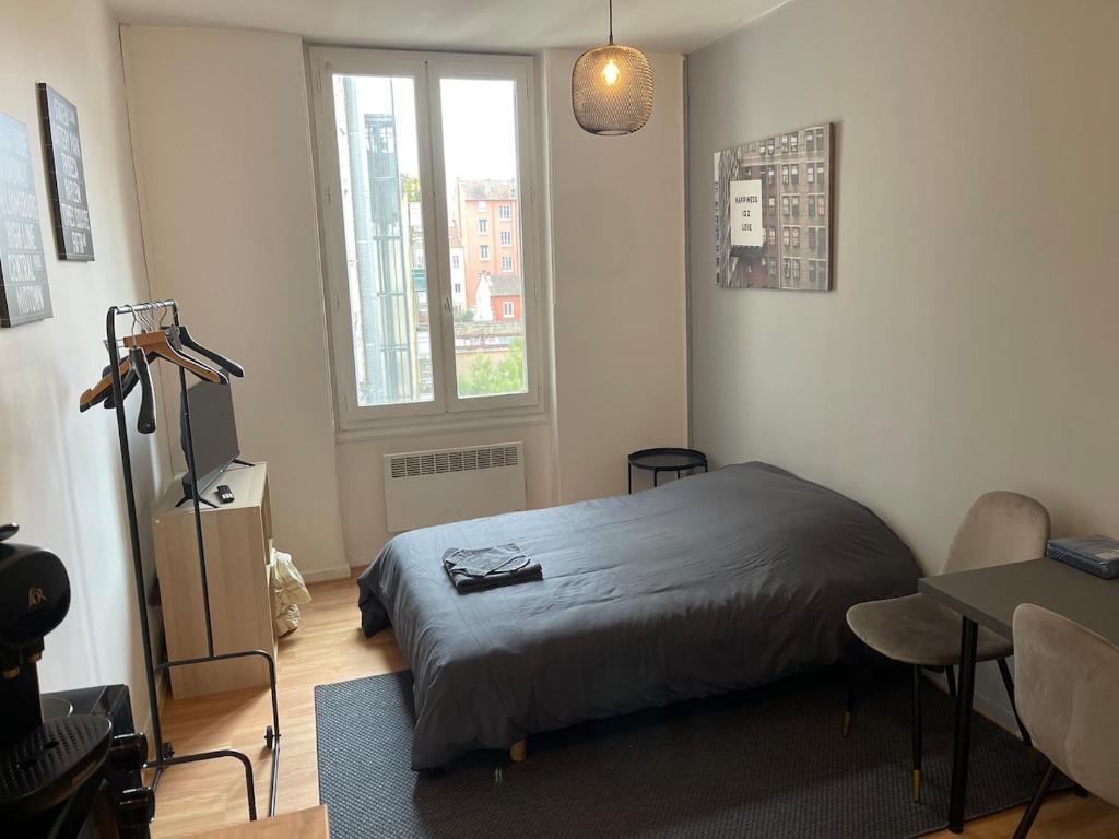 une chambre avec un lit, une table et une fenêtre dans l'établissement Studio Hôtel Villeurbanne Centre, à Villeurbanne