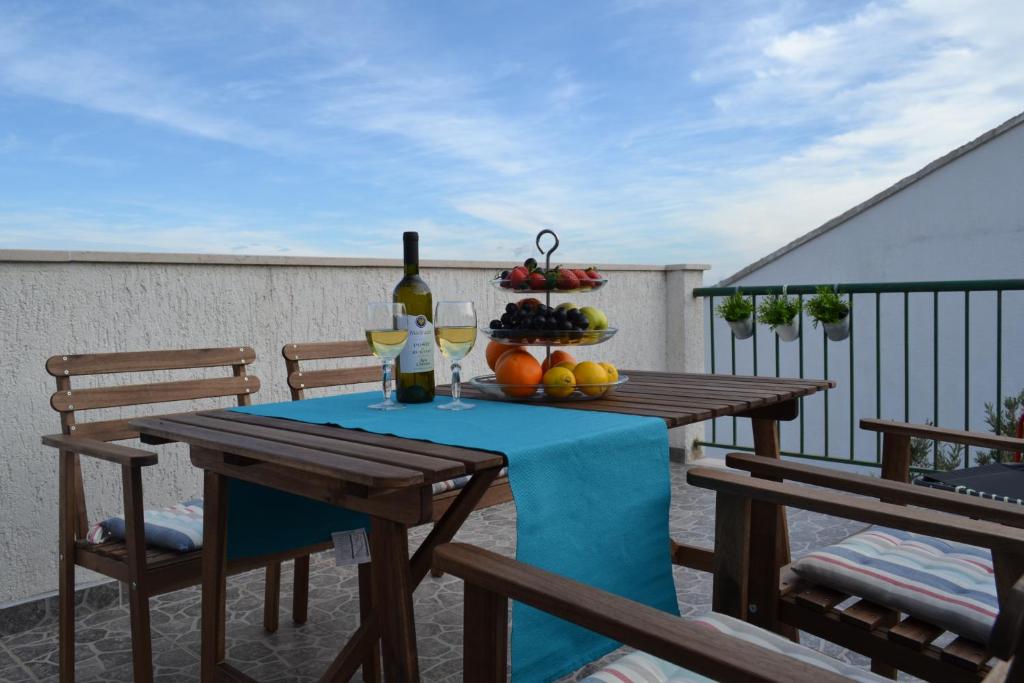 uma mesa com uma garrafa de vinho e fruta numa varanda em Apartment Bruna em Stomorska