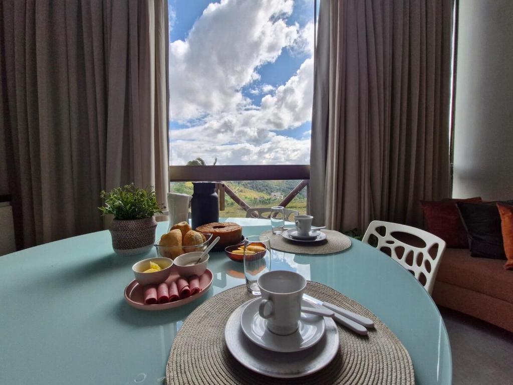 a dining room table with food and a large window at Melhor Apartamento de Bananeiras 3 quartos in Bananeiras