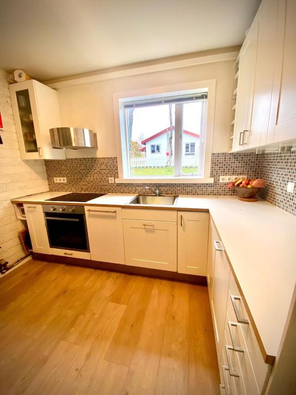 una cucina con mobili bianchi, un lavandino e una finestra di Oskars Cabin a Reykjavik