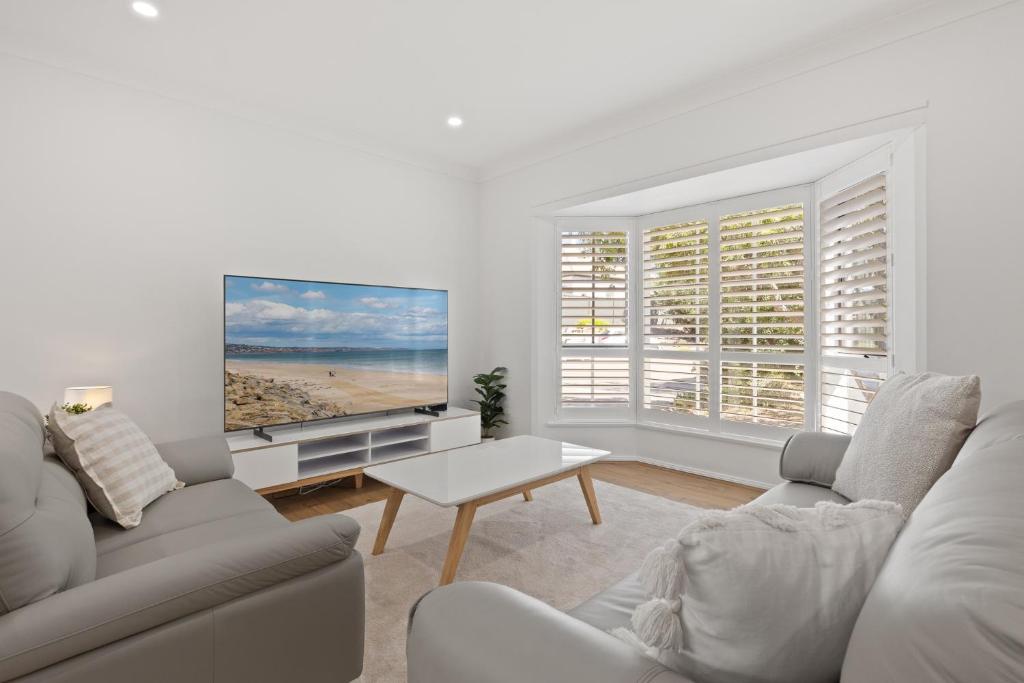 a living room with a couch and a flat screen tv at Stylish 3-Bed House Close to Attractions in Glenelg
