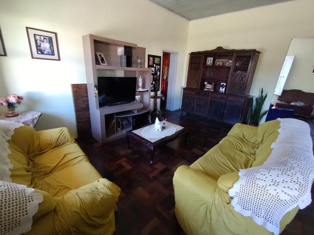 a living room with two yellow couches and a television at Hospedagem in São Gabriel