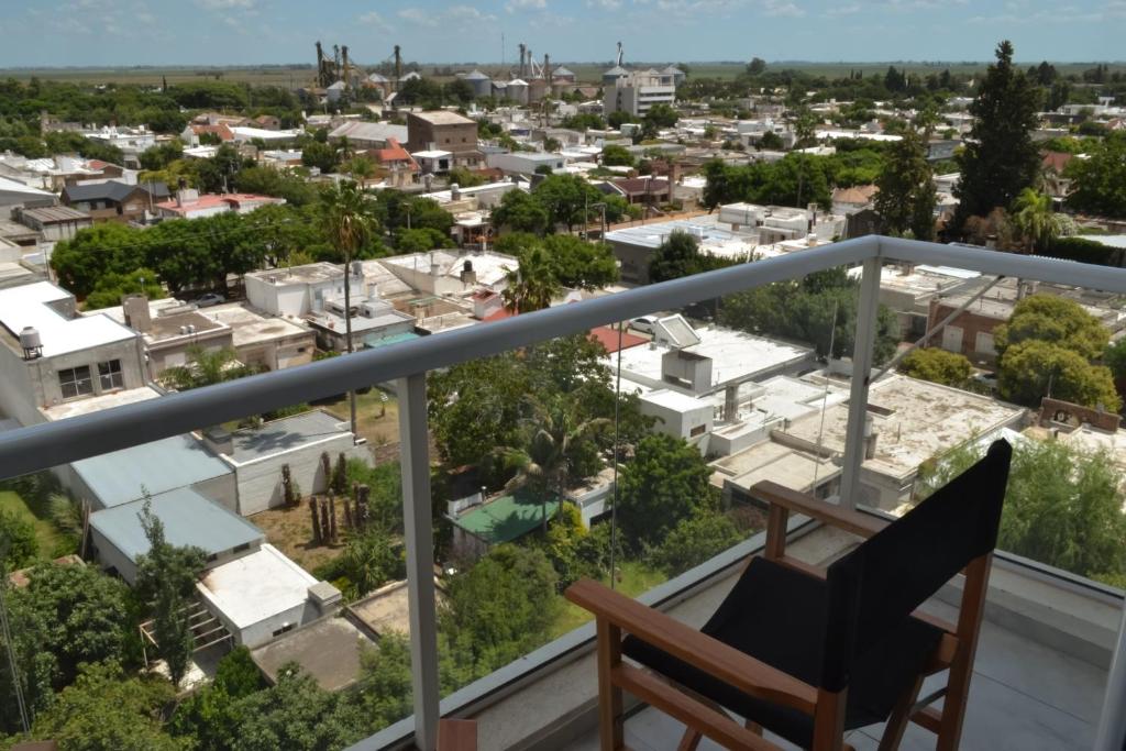a chair on a balcony overlooking a city at Departamento Buena Vista in Leones