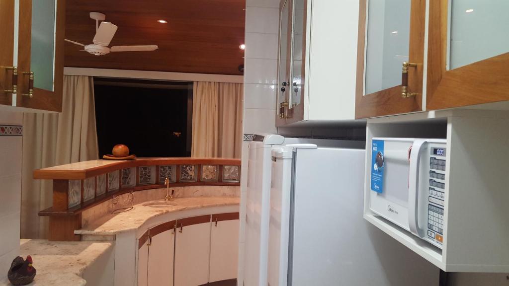 a kitchen with a white refrigerator and a sink at Apartamento Temporada Guarujá Four Seasons in Guarujá