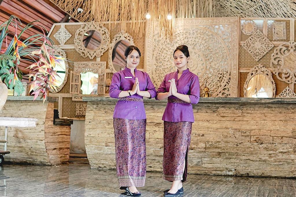 two women in purple robes standing in front of a bar at Dusun The Villas in Bawen