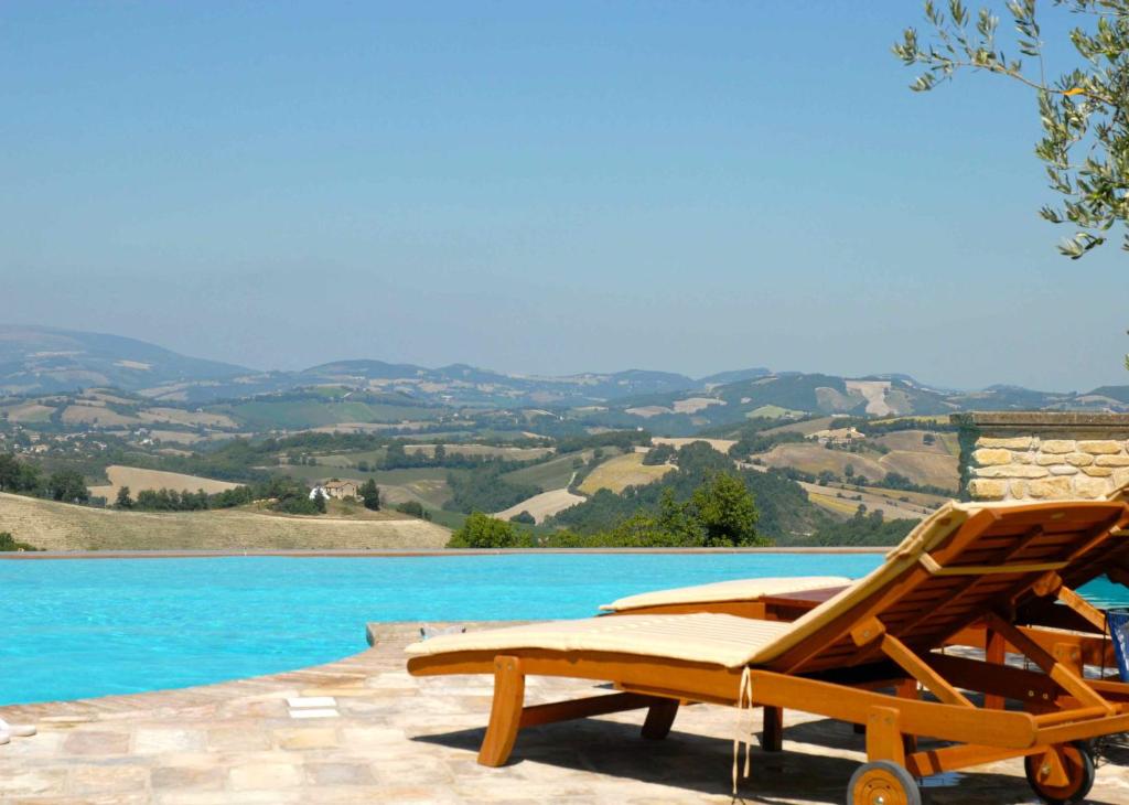 a wooden lounge chair sitting next to a swimming pool at La Corte del Gusto LuxuryApartments in Arcevia