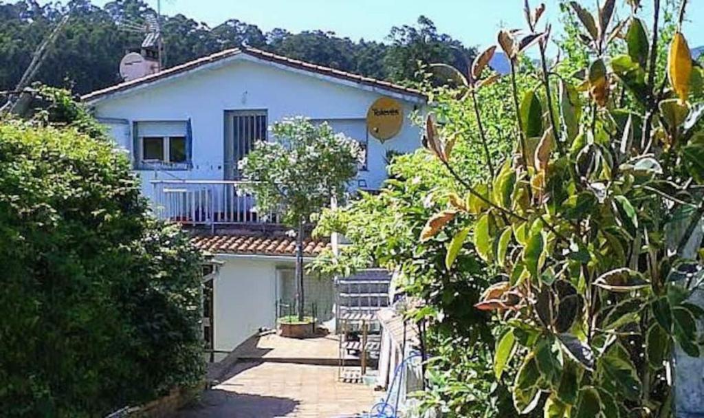 a white house with a balcony and some trees at Casa rias baixas in Poio