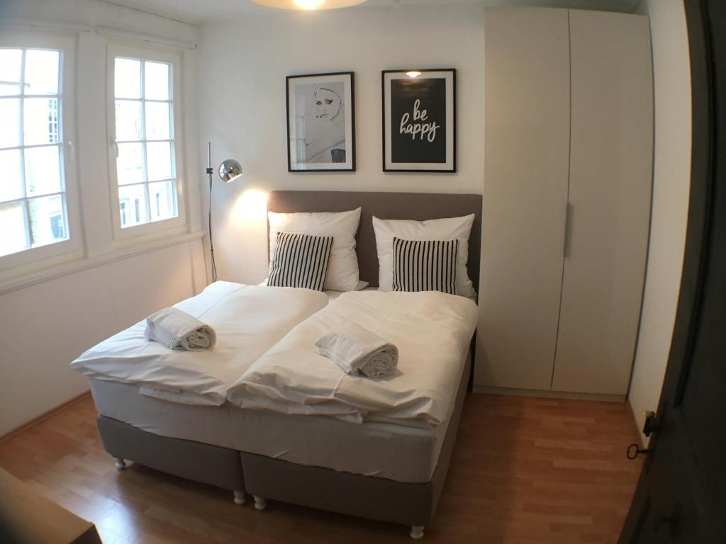 een slaapkamer met een bed met witte lakens en kussens bij Privatzimmer in bester Altstadtlage in Tübingen