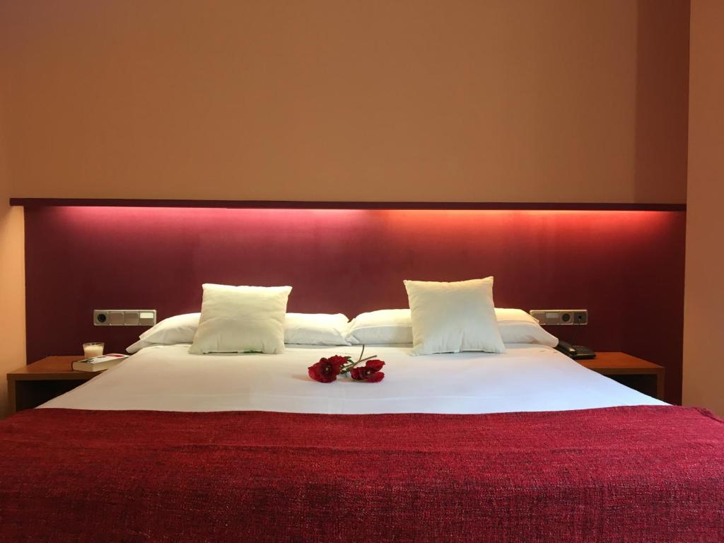 sypialnia z dużym łóżkiem z czerwonym zagłówkiem w obiekcie Hotel Jonquera w mieście La Jonquera