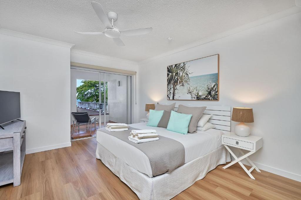 una camera da letto bianca con un letto e una televisione di Absolute Beachfront One Bedroom Alassio Apartment 201 Palm Cove a Palm Cove