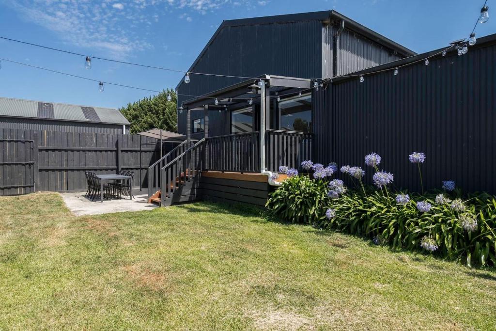 ein schwarzes Haus mit Blumen im Hof in der Unterkunft The Cottage at Oak Tree Farm - Vineyards & Wildlife in Hastings