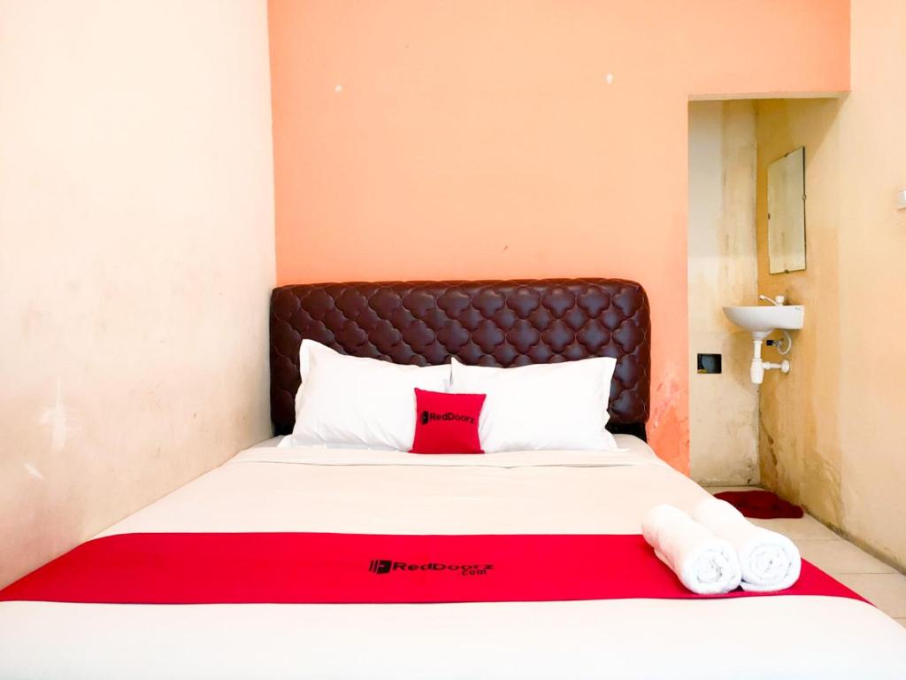 a bed with a red blanket and two towels on it at RedDoorz near City of Tomorrow Mall Surabaya in Surabaya