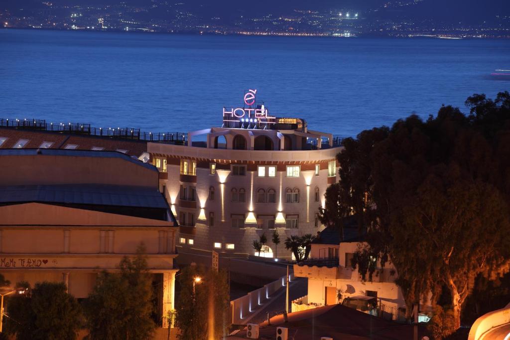 un hotel con un cartel encima de él por la noche en E' Hotel, en Reggio Calabria