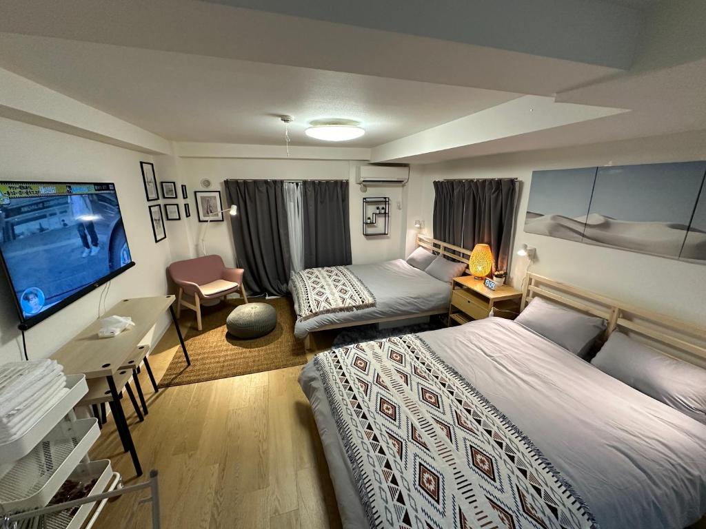 a hotel room with two beds and a flat screen tv at 新宿神楽坂近く寿司店2 in Tokyo