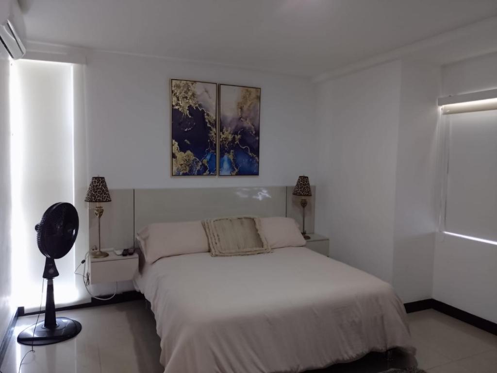 ein weißes Schlafzimmer mit einem Bett und einem Gemälde an der Wand in der Unterkunft Modern Apartment Prime Location, Comfortable Apartment in Barranquilla