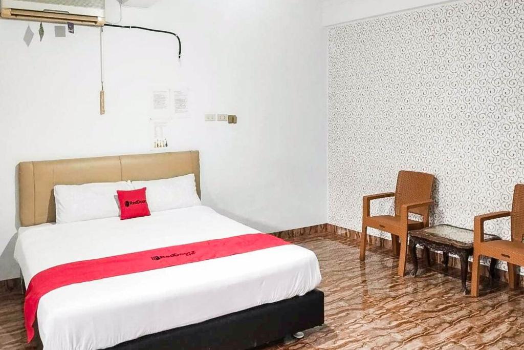 a bedroom with a bed and two chairs in it at RedDoorz at Amanah Syariah Residence Tanjung Karang Lampung in Tanjungkarang