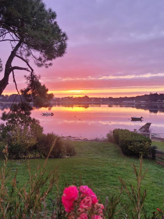 un coucher de soleil sur un lac avec des bateaux dans l'eau dans l'établissement Havre de Paix les pieds dans l'eau, à Locoal-Mendon
