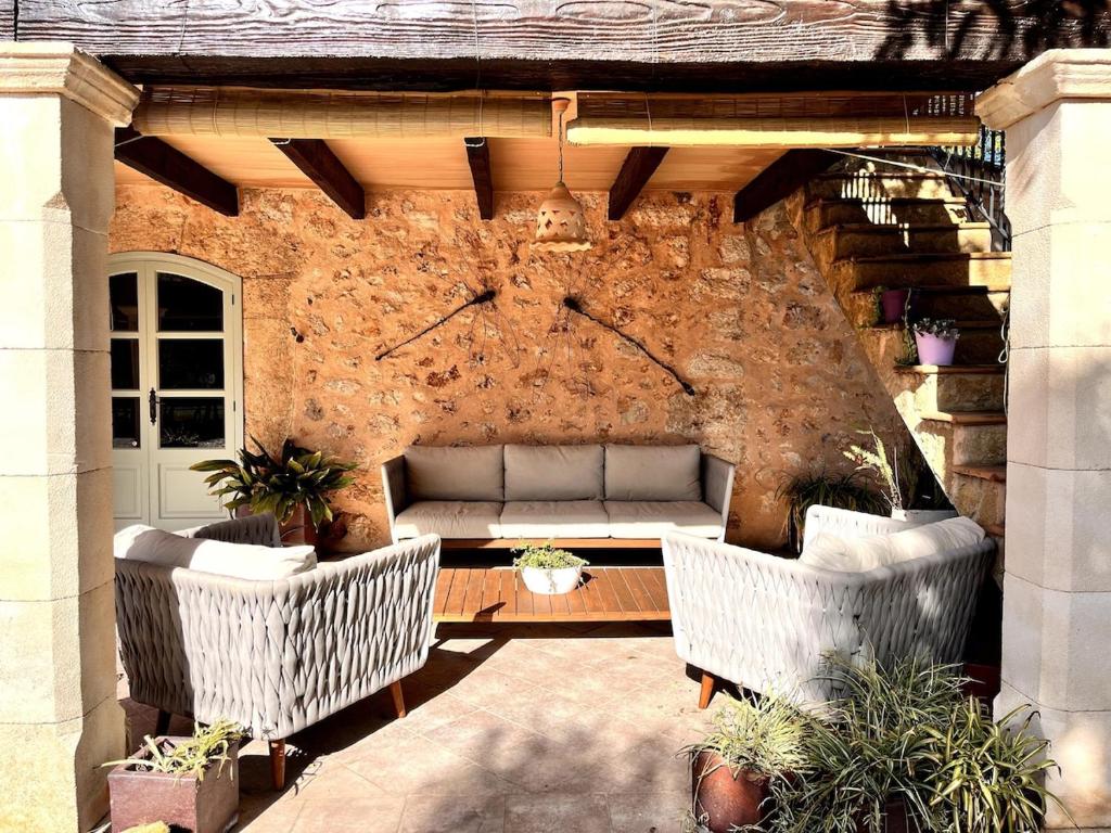 eine Terrasse mit zwei weißen Korbstühlen und einer Steinmauer in der Unterkunft Cream homes Son Celles, ETV3533 in Sencelles