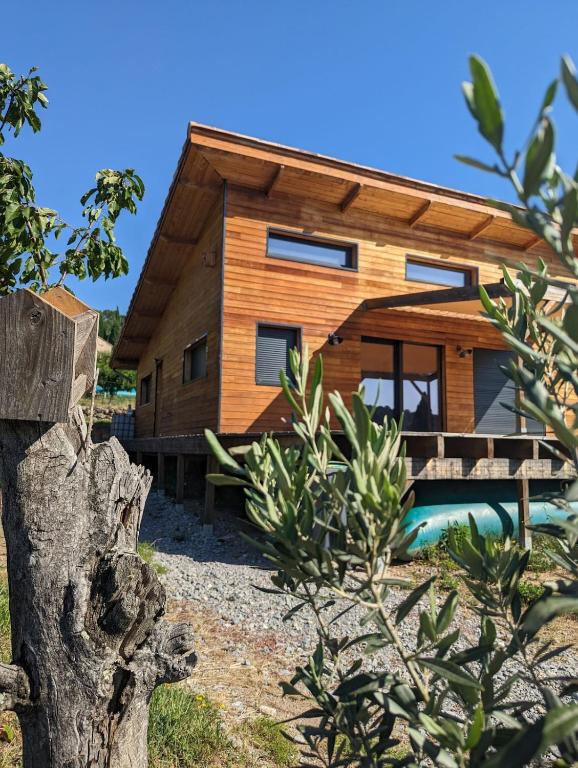 une maison en bois avec une piscine en face de celle-ci dans l'établissement Maison bois au calme, à Ailhon