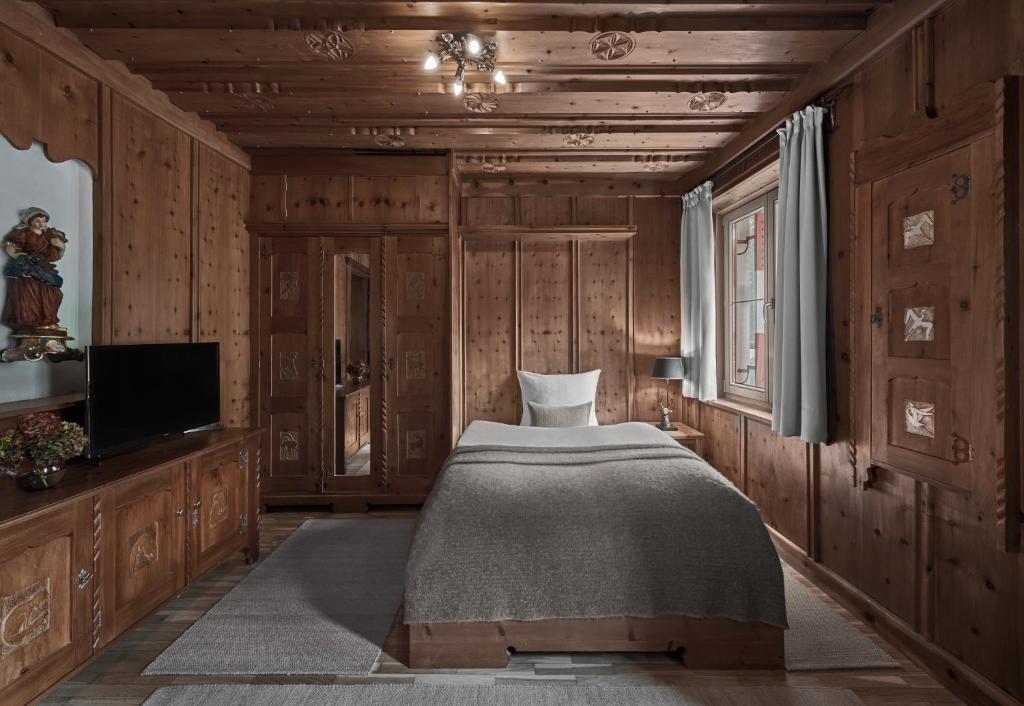 a bedroom with a bed and a tv and wooden walls at Hotel Goldener Greif in Kitzbühel