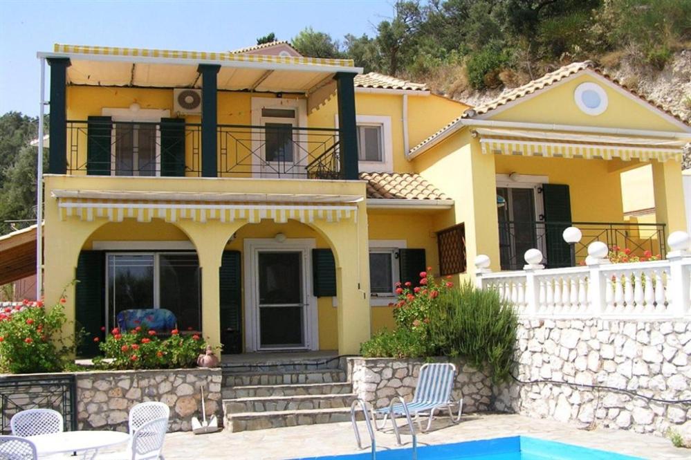 a yellow house with a pool in front of it at Villa Mike's House in Apolpaina