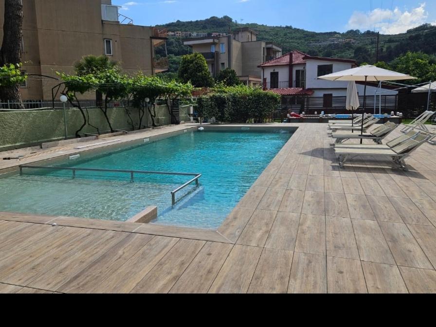 a large swimming pool with chairs and an umbrella at Holiday Gufetto in Pietra Ligure
