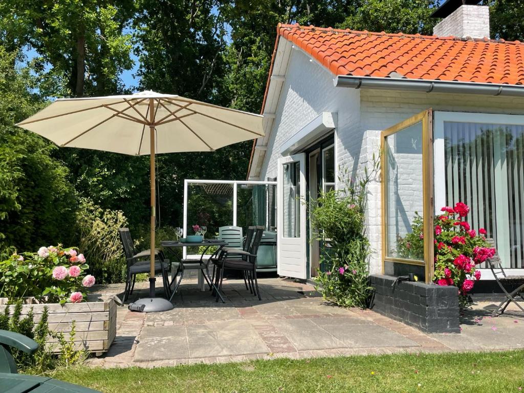 a patio with an umbrella and a table and chairs at Holiday home Zeeroos in Koudekerke