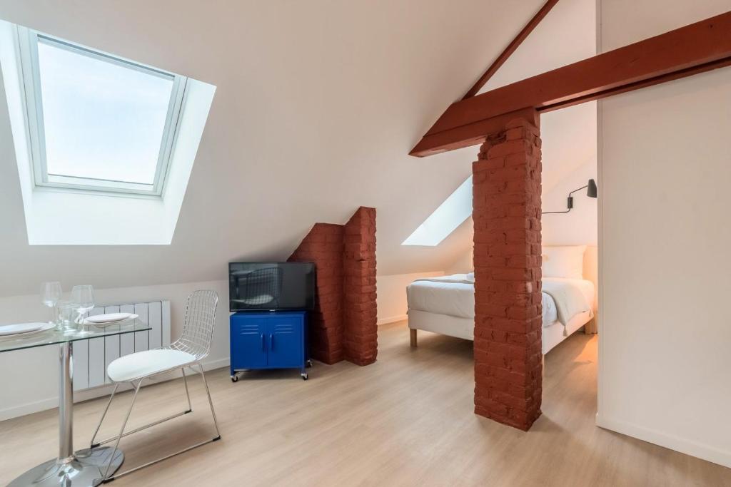 une chambre avec un lit, un bureau et une télévision dans l'établissement Studio sous les combles côté rue, parking gratuit, à Villeneuve d'Ascq