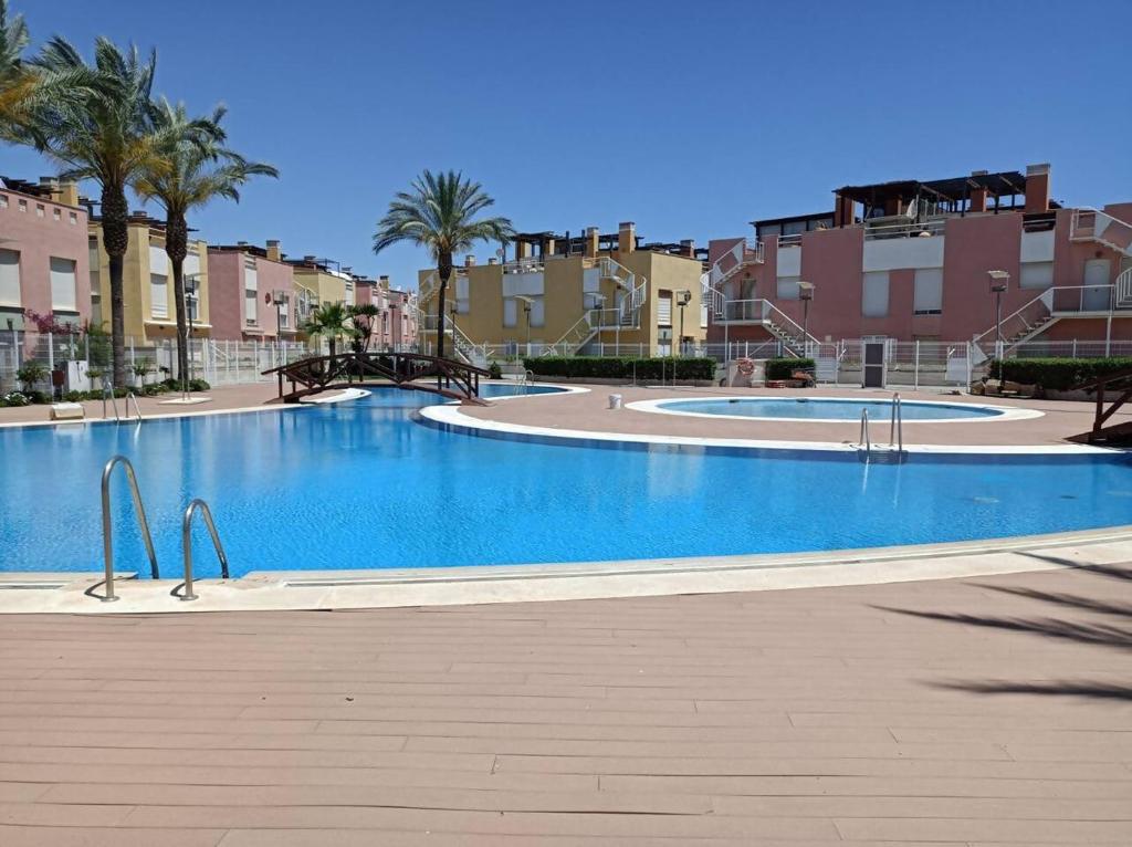 ein großer Swimmingpool mit Palmen und Gebäuden in der Unterkunft Vera Playa Apto 1-4 Personas Piscina Parking WI-FI in Playas de Vera