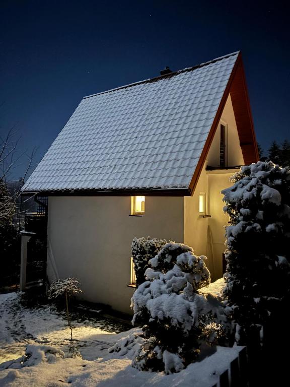 a house with a snow covered roof with lights on it at Dom Na Wzgórzu in Poręba