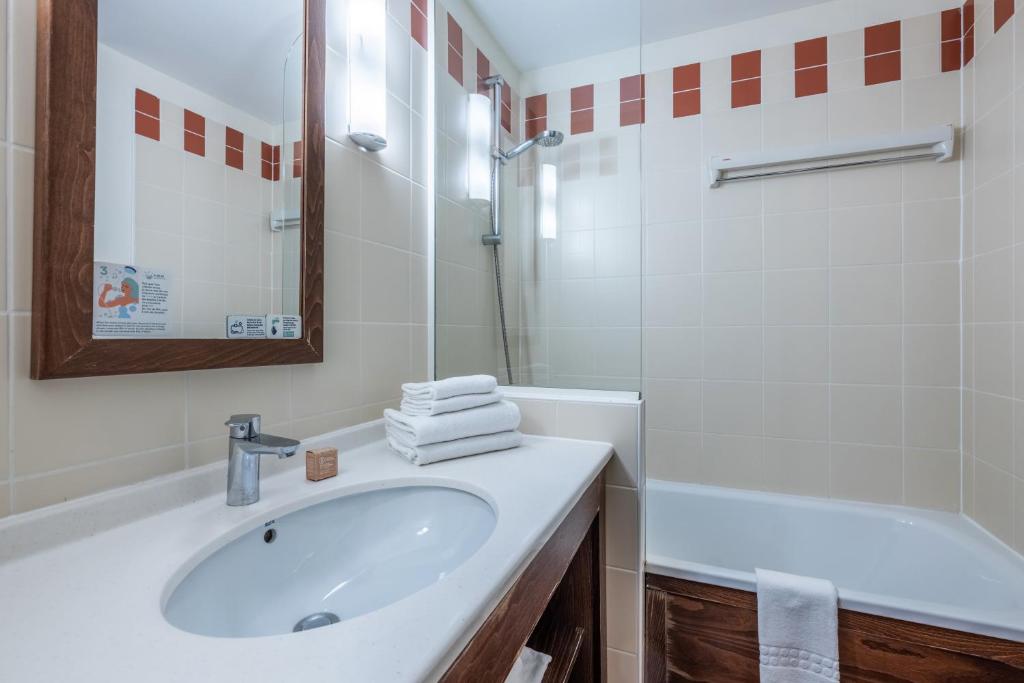 a white bathroom with a sink and a bath tub at Résidence Pierre & Vacances Le Belmont in Arc 1800