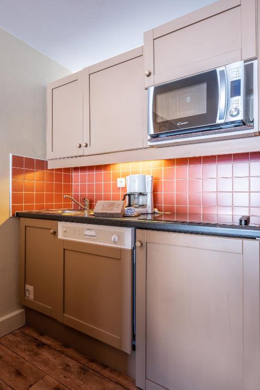 a kitchen with white cabinets and a microwave at Résidence Pierre & Vacances Le Belmont in Arc 1800