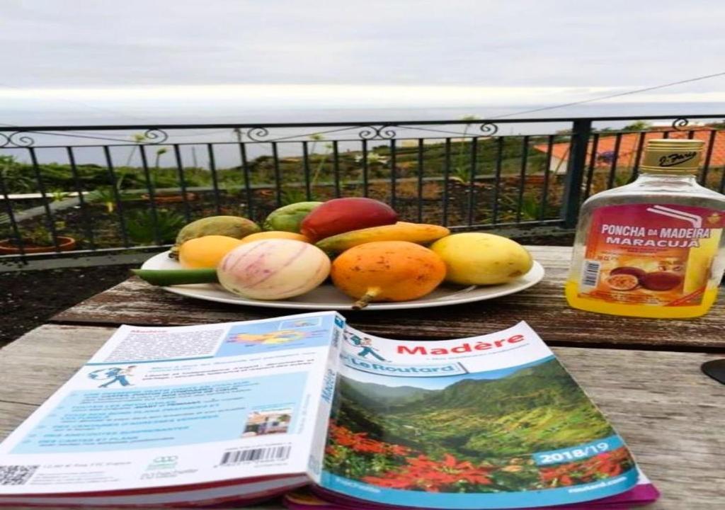 einen Obstteller auf einem Tisch mit einer Flasche Alkohol in der Unterkunft Paraiso das Flores in Estreito da Calheta