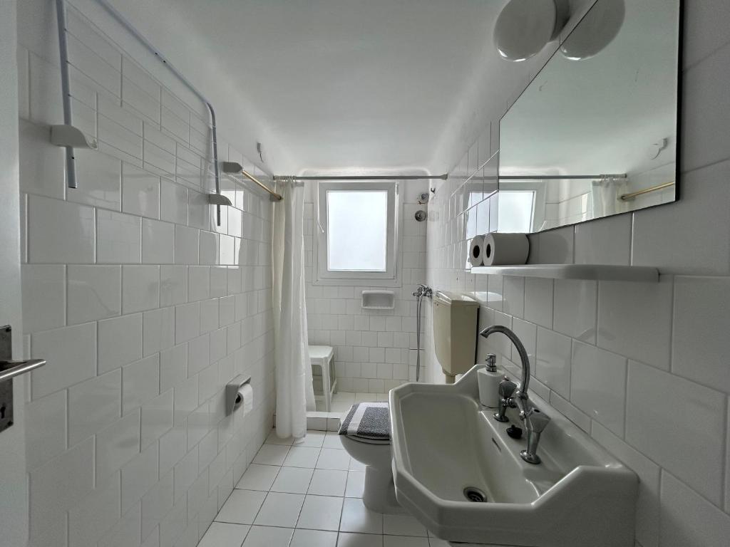 biała łazienka z umywalką i toaletą w obiekcie Tinion Urban Hotel w mieście Tinos