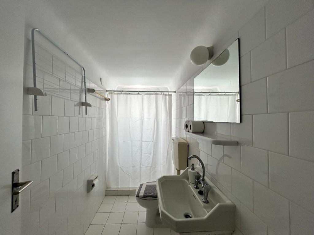 biała łazienka z umywalką i lustrem w obiekcie Tinion Urban Hotel w mieście Tinos