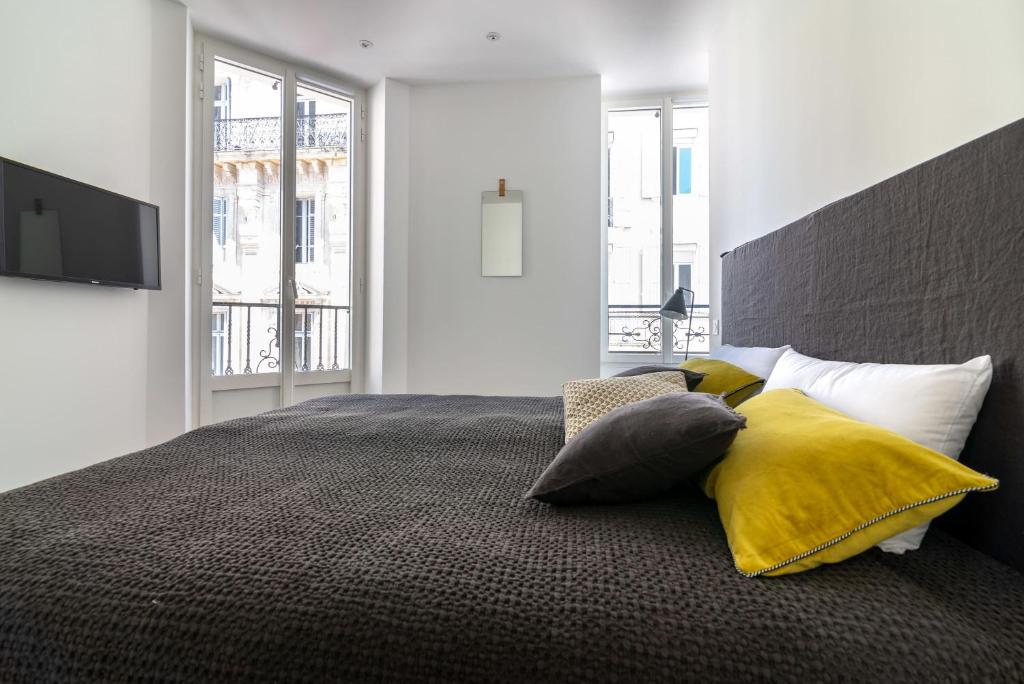 une chambre avec un grand lit avec un oreiller jaune dans l'établissement Scandinavian Urban 2 - 2BR apartment in center close to Palais des Festivals and the beach, à Cannes