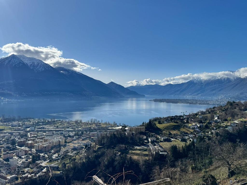 a view of a city and a lake with mountains at Casa Reto - Das Ferienhaus im Tessin in Gordola
