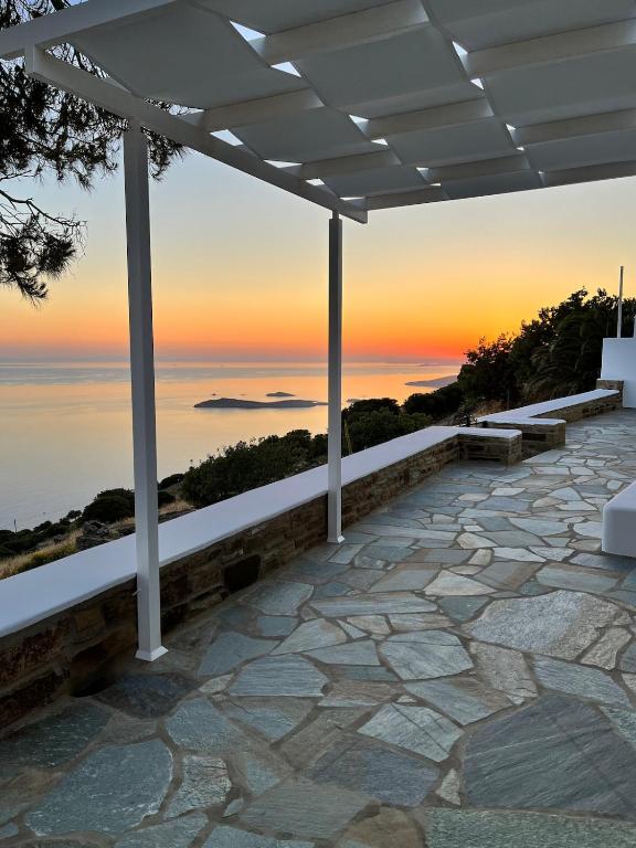 a patio with a view of the ocean at sunset at Villa Eleni - At the Top! in Apróvaton