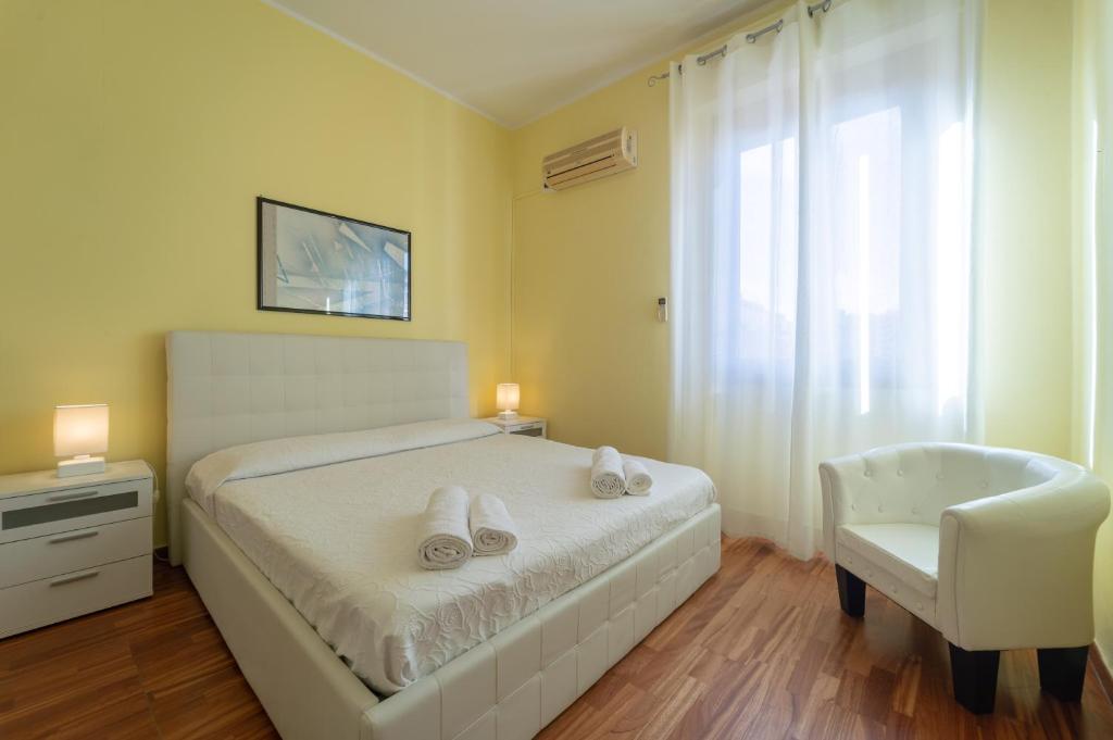 a bedroom with a white bed and a chair at Apartments via Spano in Alghero
