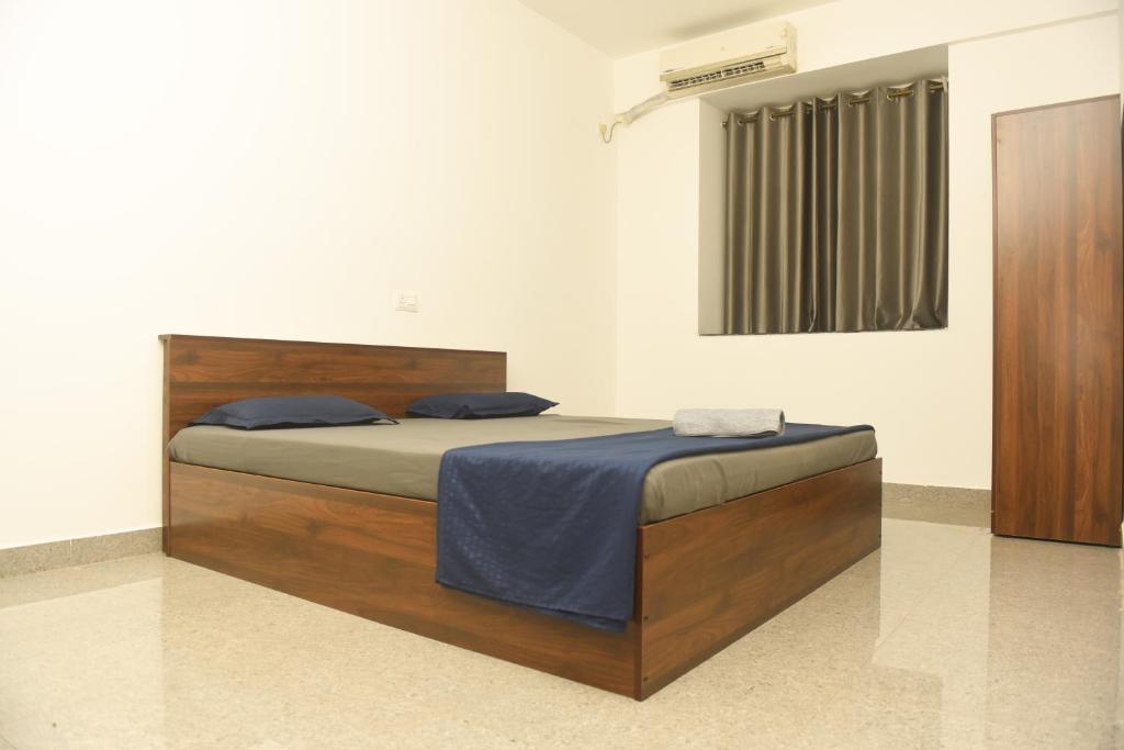 a bed in a room with a wooden bed frame at Sai Homestay Panaji 2 BHK, 1 BHK and Studio Apartment in Panaji