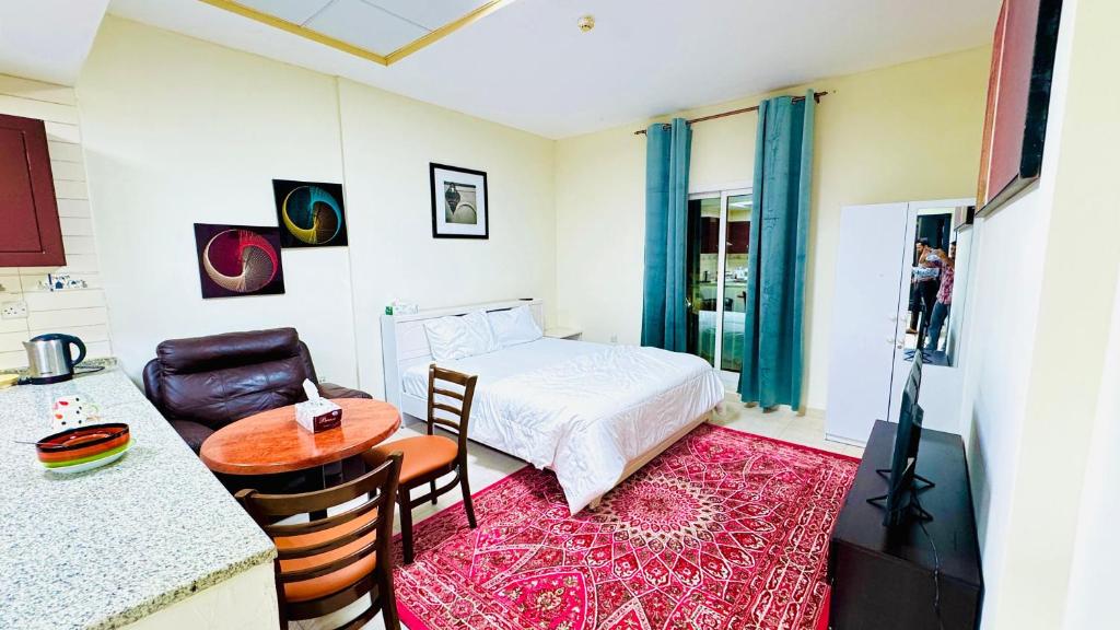 ドバイにあるYour Perfect 1BHK Apartmentのベッドとテーブルと椅子のある小さな部屋