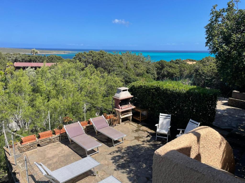 a patio with chairs and a grill and the ocean at Villa Vista in Stintino